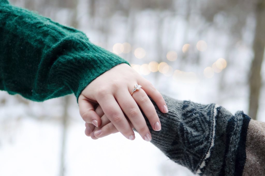 Close-up of two hands and an engagement ring