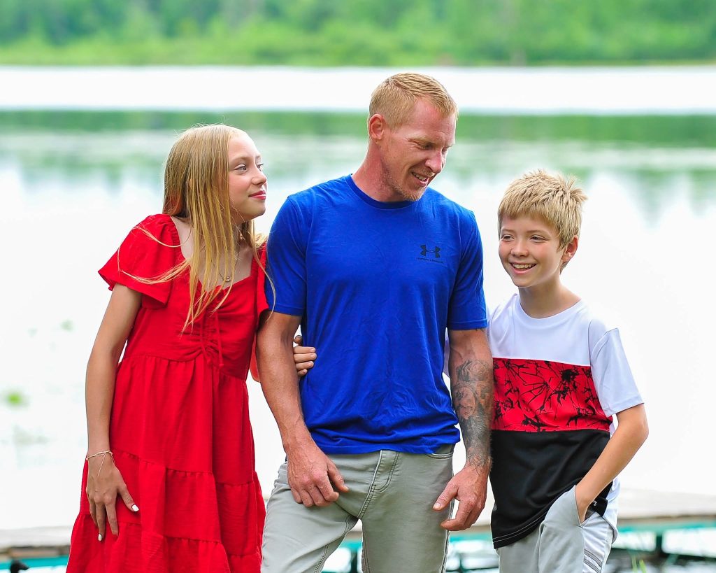 Father and two children smiling at a lakeside session