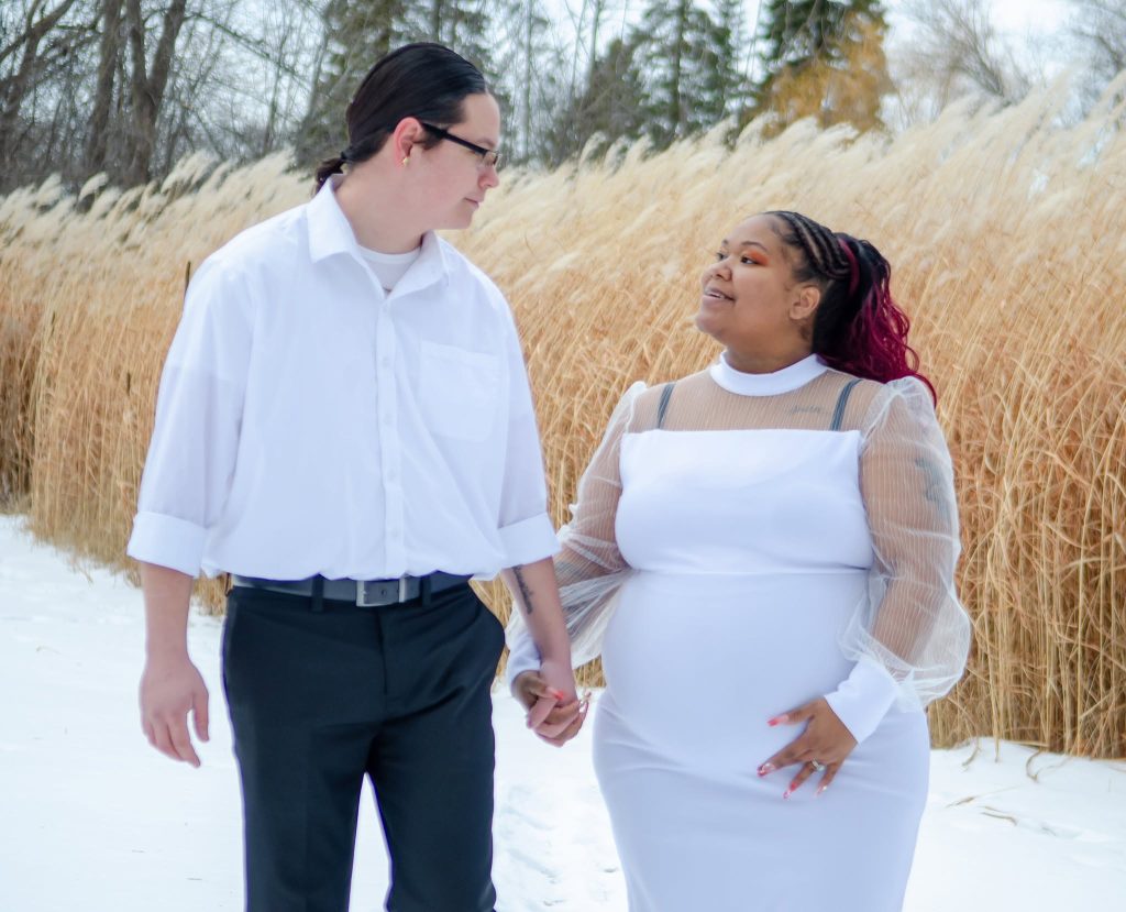 Expecting couple holding hands in winter grasses