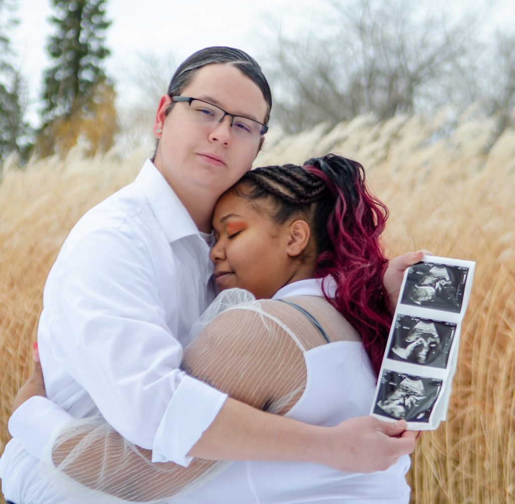 Expecting couple embracing with ultrasound photos