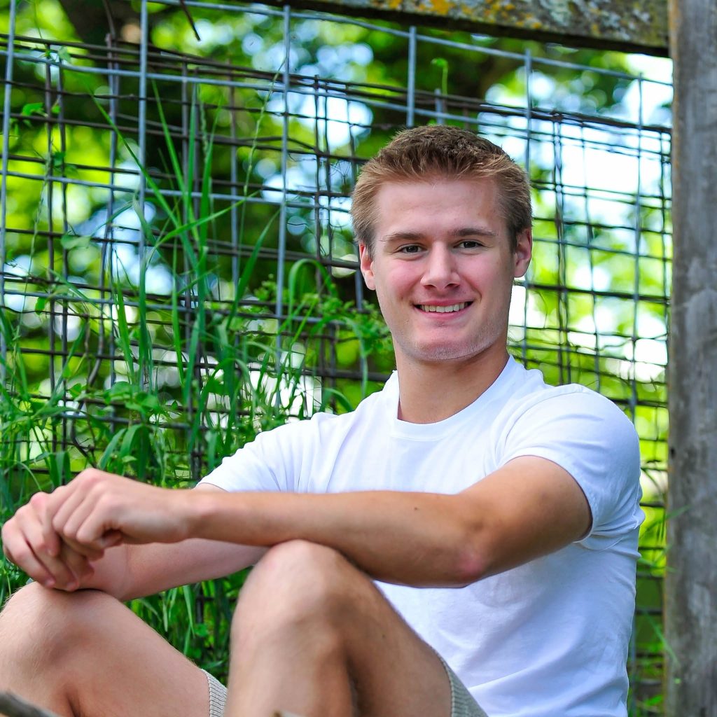 Close senior portrait by a wire fence